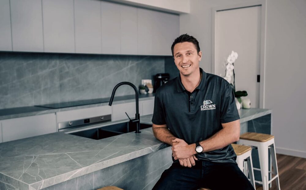 Crown Construction director smiles in a pristine kitchen from their brand story video, reflecting pride and company excellence.